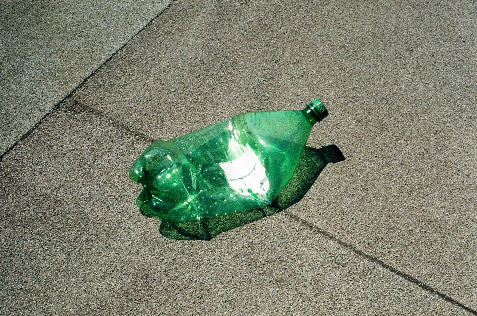 A crushed green plastic bottle on concrete