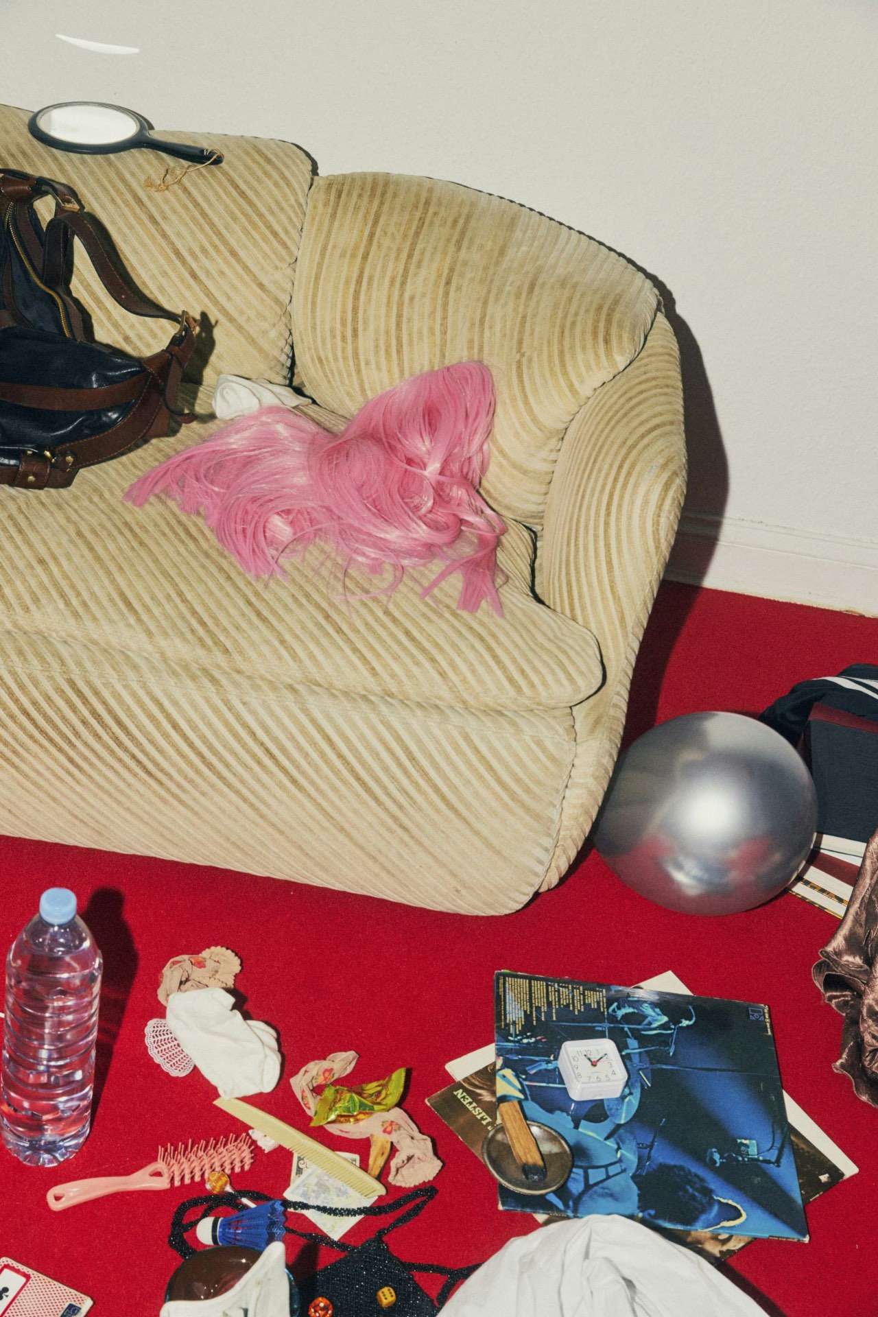 A mindfully cluttered scene — pink wig on a corduroy couch